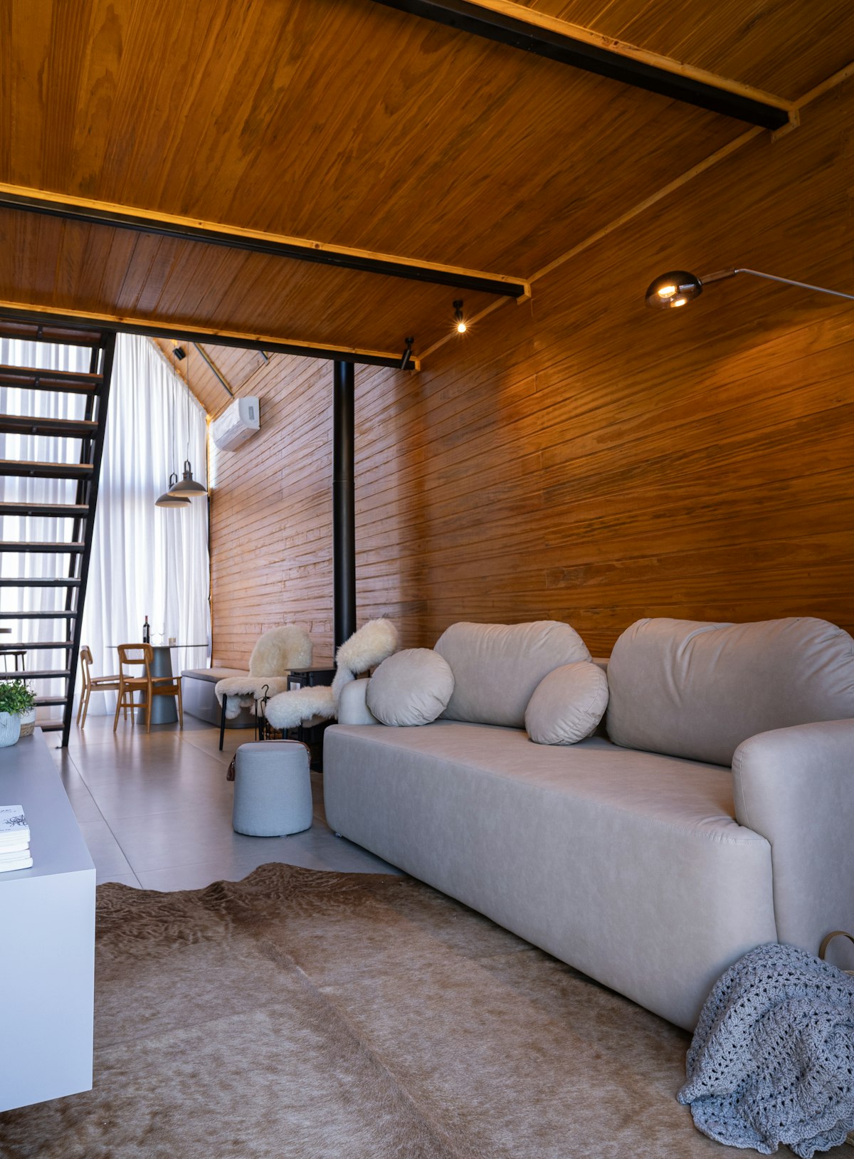 Living room under a slatted timber ceiling with a low white sofa