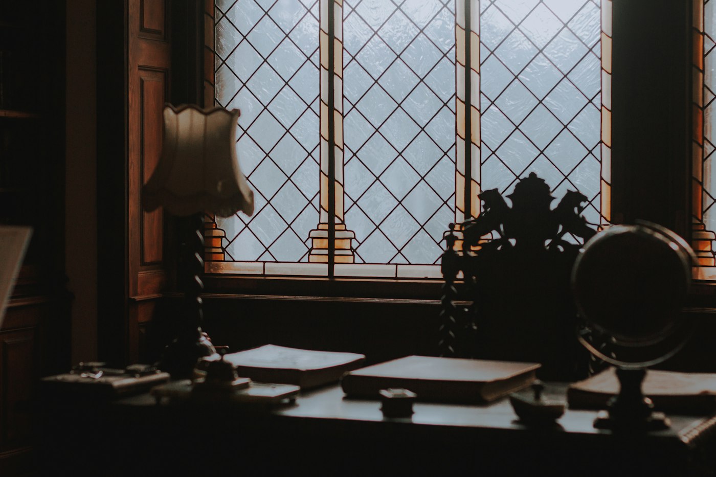 Study with a timber desk and brass lamp beside a leaded window